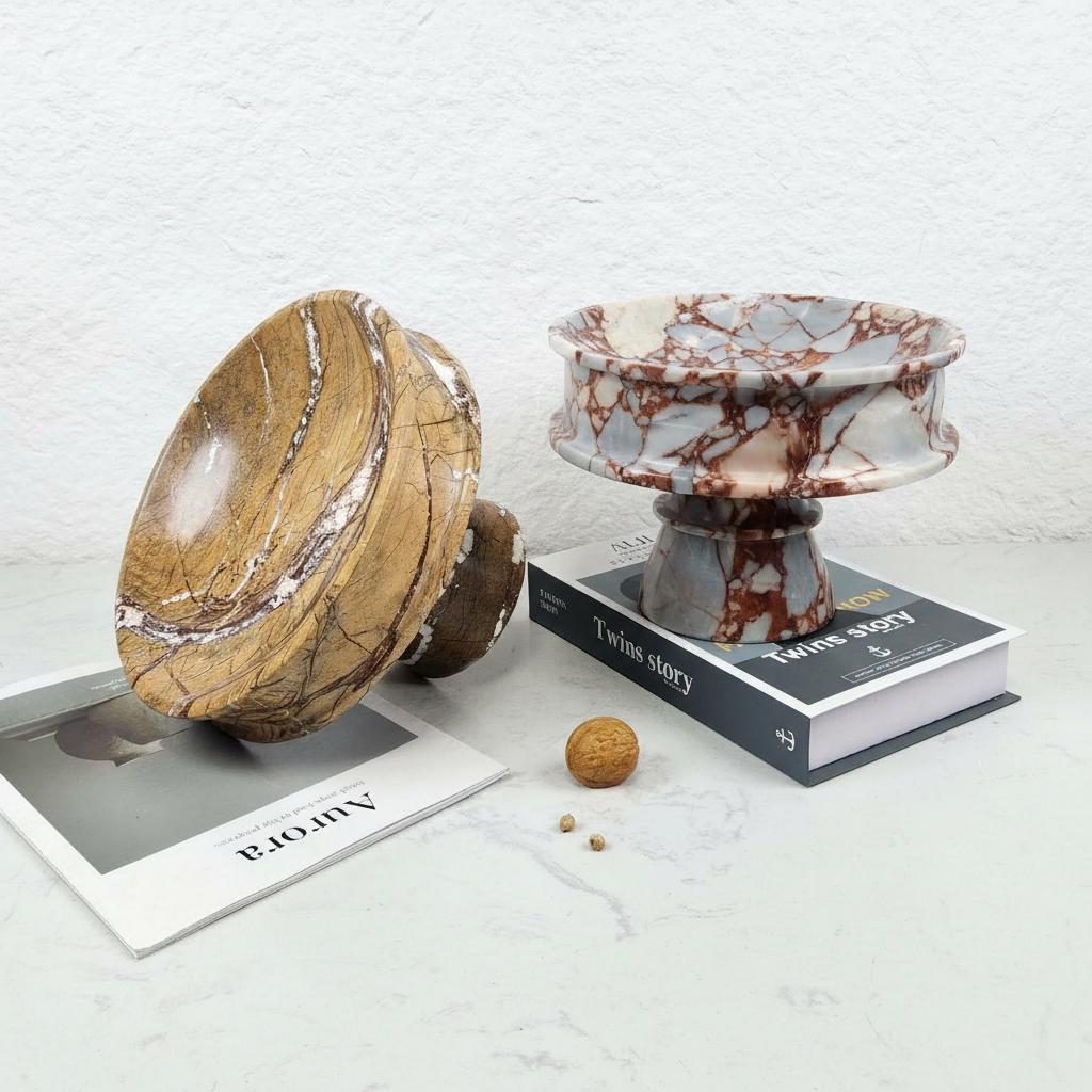 Two marble footed bowls on books showcasing color variations