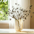 Marble-pattern glass cylindrical vase with dried botanicals on table