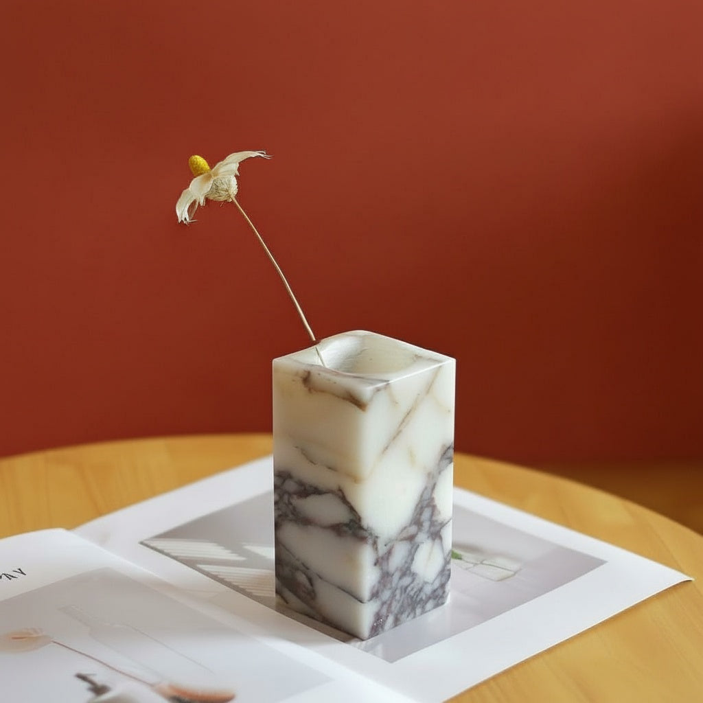 White marble rectangular bud vase with dark veining on a wooden table