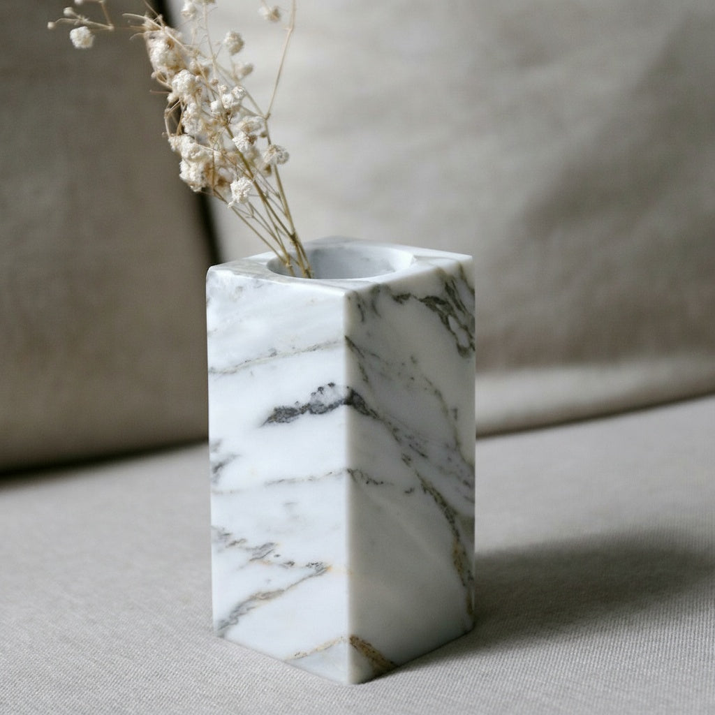 Solid marble block bud vase with dried botanicals on a textured fabric surface