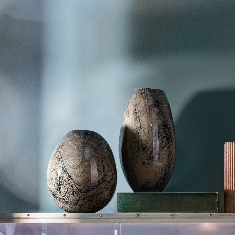 Group shot of tall and round marbled glass vases on shelf