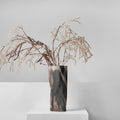 Full view of matte black and bronze ceramic vase with dried botanicals