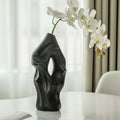 Matte black ceramic abstract vase with white orchids on table