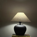 Matte black ceramic table lamp lit in dark room