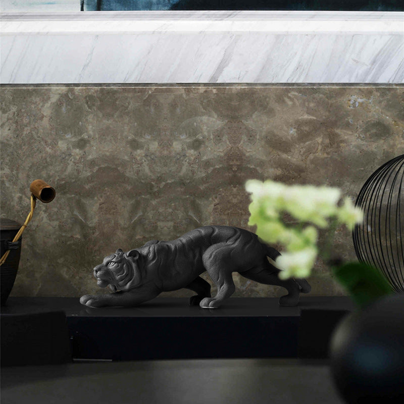 Matte black ceramic tiger sculpture in crouching pose on shelf