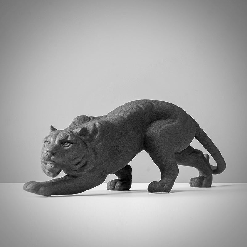 Side view of crouching ceramic tiger sculpture