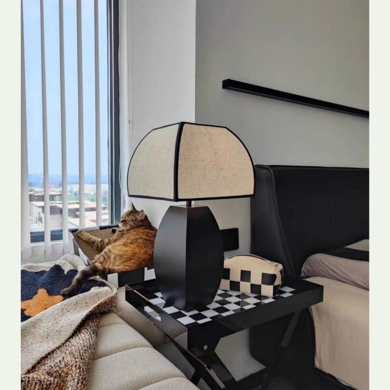 Matte black and linen lamp in bedroom setting next to bed