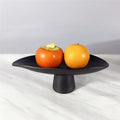 Front view of large and medium matte black pedestal bowls with fruit