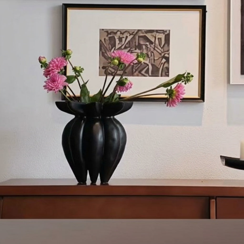Matte black sculptural fluted vase styled on a wooden console table