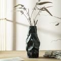 Matte black textured ceramic vase with dried branches on table