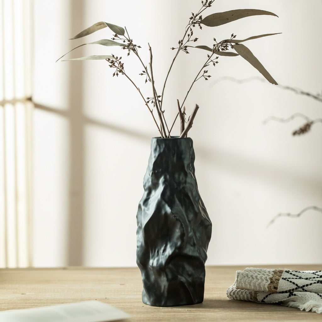 Matte black textured ceramic vase with dried branches on table