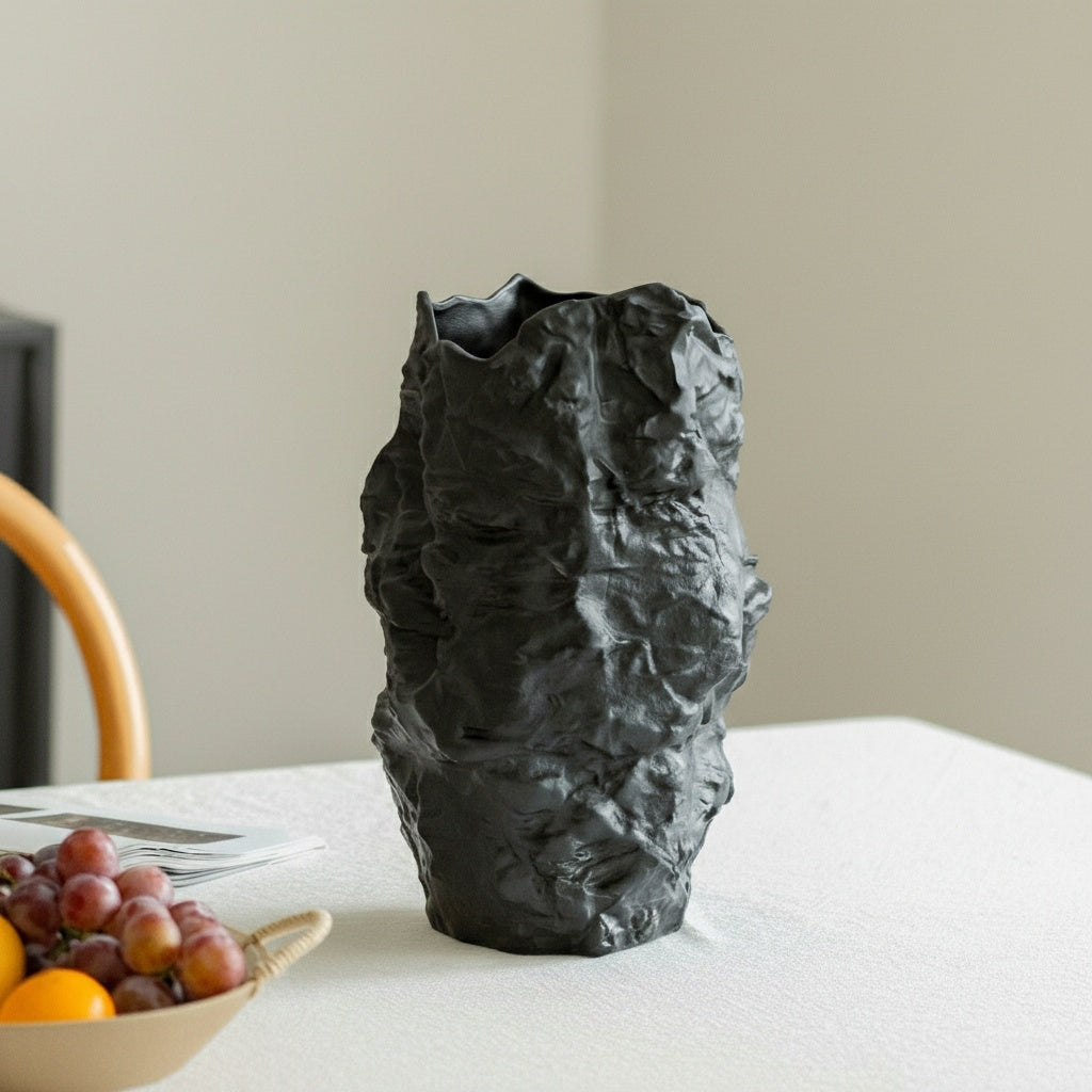 Close up of empty matte black ceramic vase with crinkled rock texture on a table