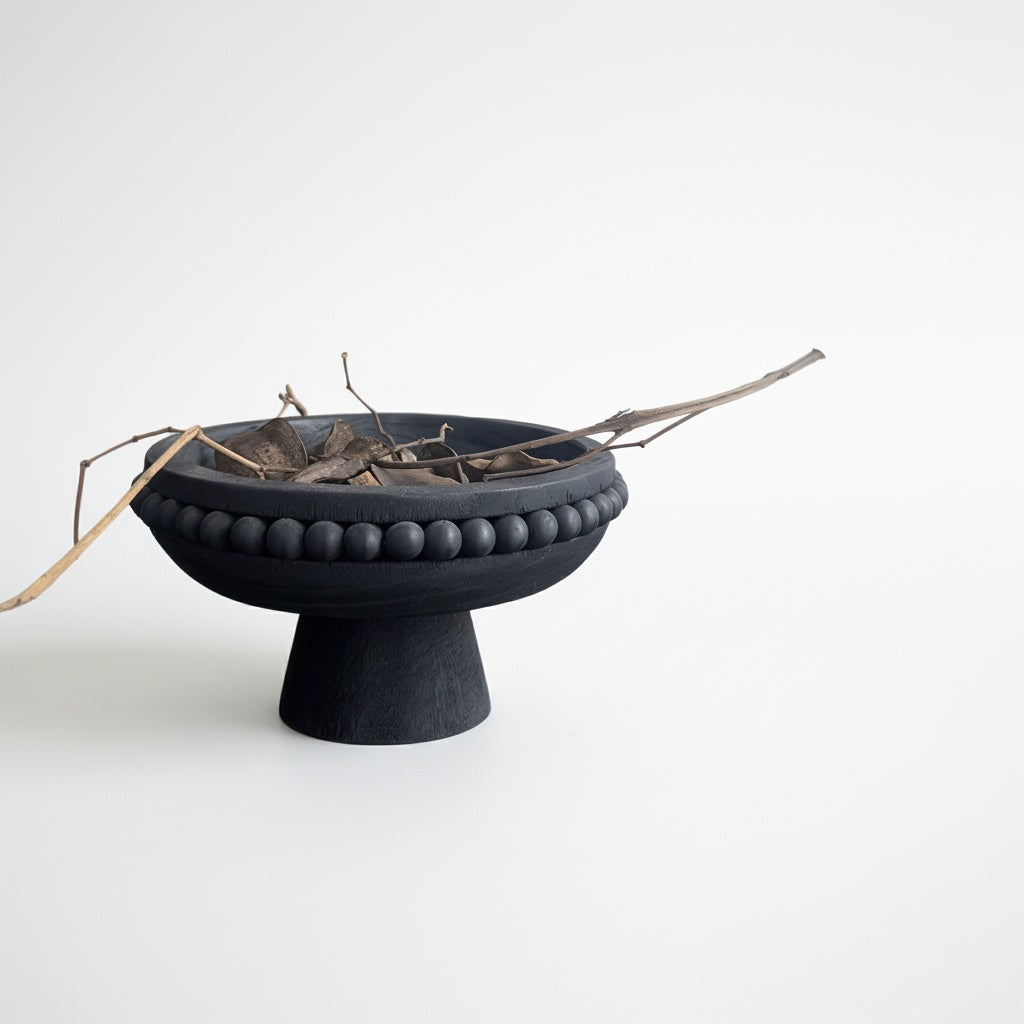 Matte Black Wooden Beaded Pedestal Bowl styled with dried botanical leaves