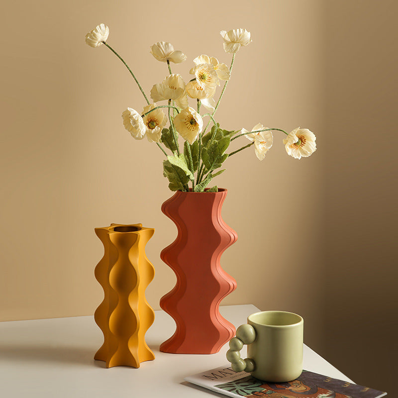 Matte ceramic sculptural wave vases in orange and yellow on table