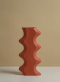 Side profile of tall orange sculptural wave vase