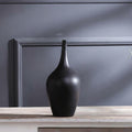 Close up of black matte ceramic vase on wooden table
