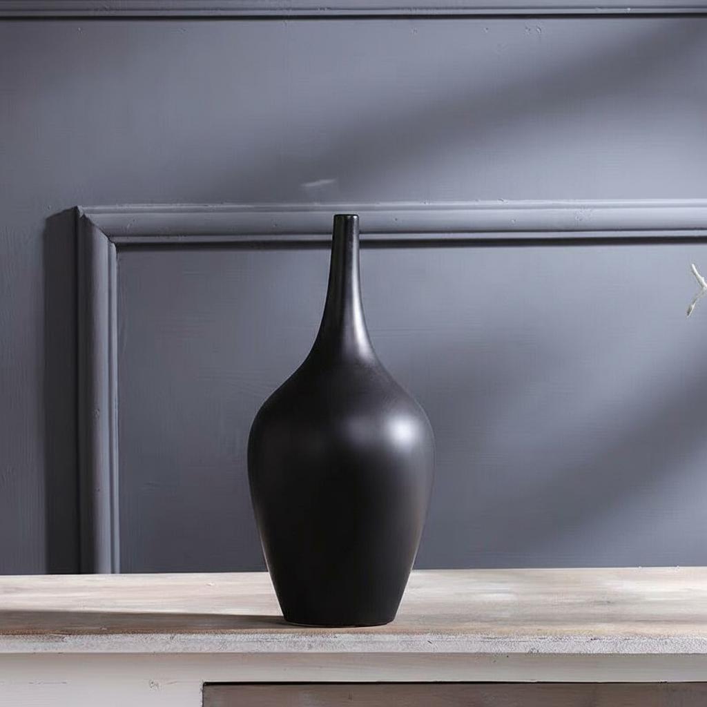 Close up of black matte ceramic vase on wooden table