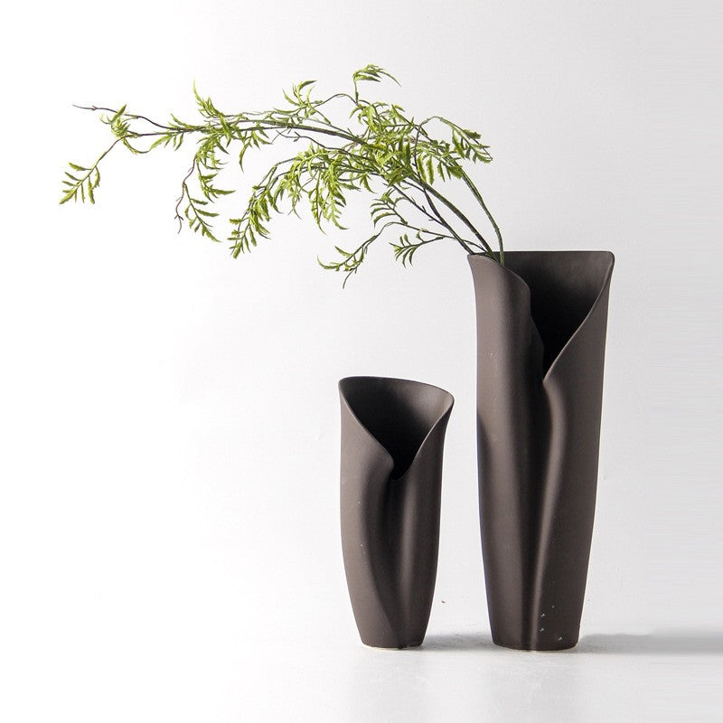 Matte charcoal ceramic vases in organic folded shape with greenery