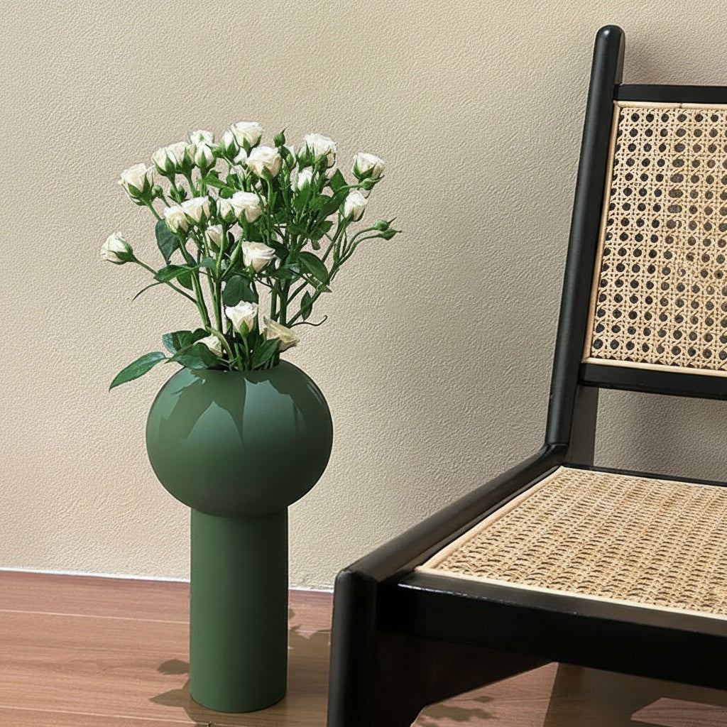 Matte green ceramic vase with white roses on floor next to chair