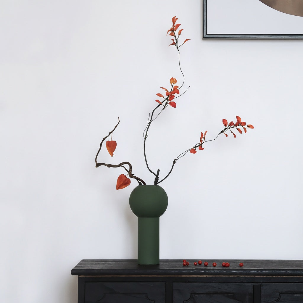 Geometric green vase with autumn branches on sideboard