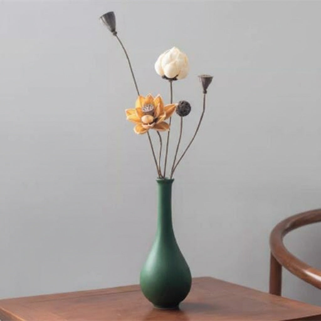 Matte green glazed teardrop vase with dried botanicals on wooden table
