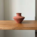 Front view of matte terracotta sculptural vase on wooden shelf
