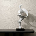 Matte White Abstract Sculpture on black table against textured wall