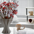 Matte white ceramic ruffled wave vase with red flowers on table