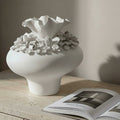 Matte white ceramic sculptural floral vase on a textured stone console