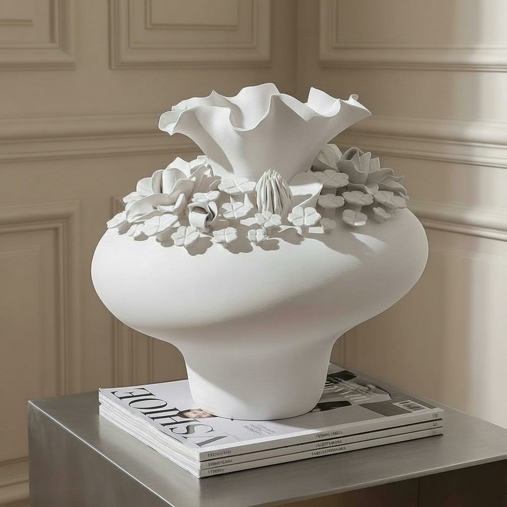 Matte white ceramic sculptural floral vase styled on top of stacked magazines