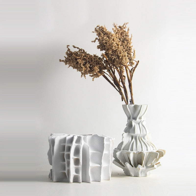 Two matte white sculptural ceramic vases with dried flowers