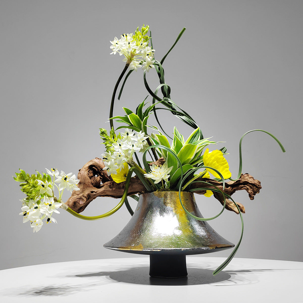 Angled view of silver and gold glazed vase with artificial flowers