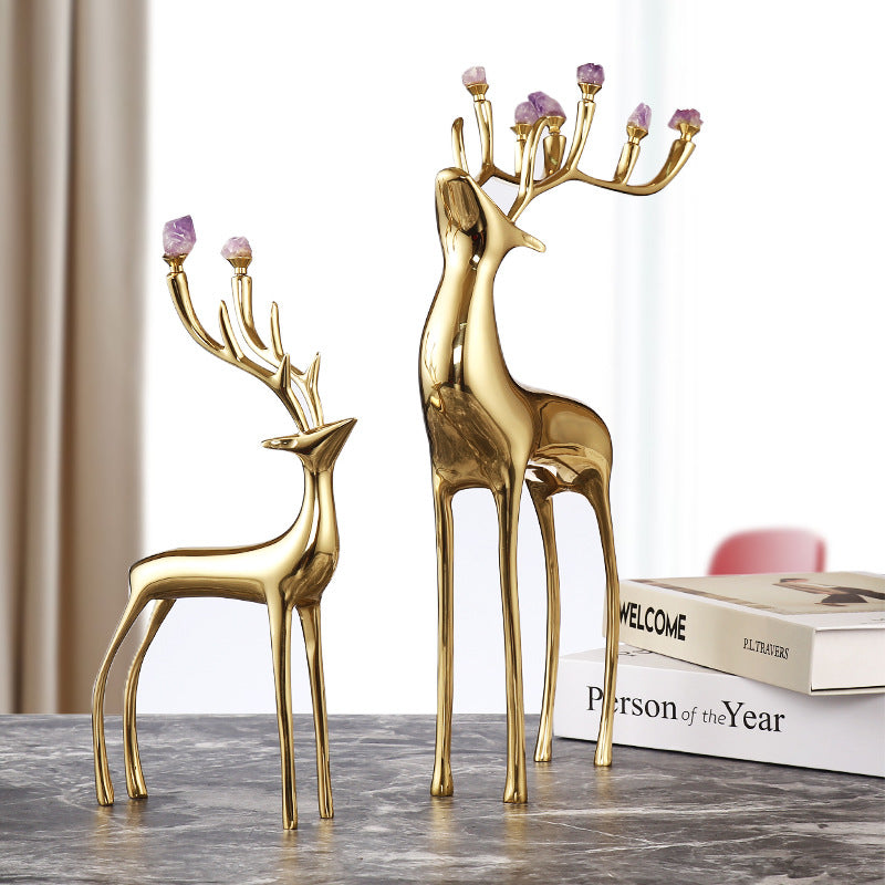 Lifestyle shot of copper deer sculptures on a grey marble surface in a living room