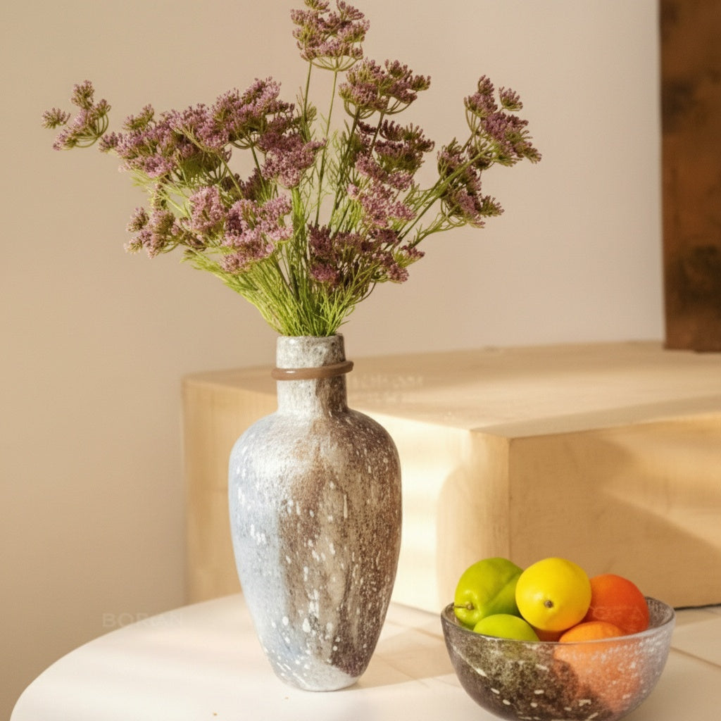 Mottled glazed ceramic vase with flowers on table
