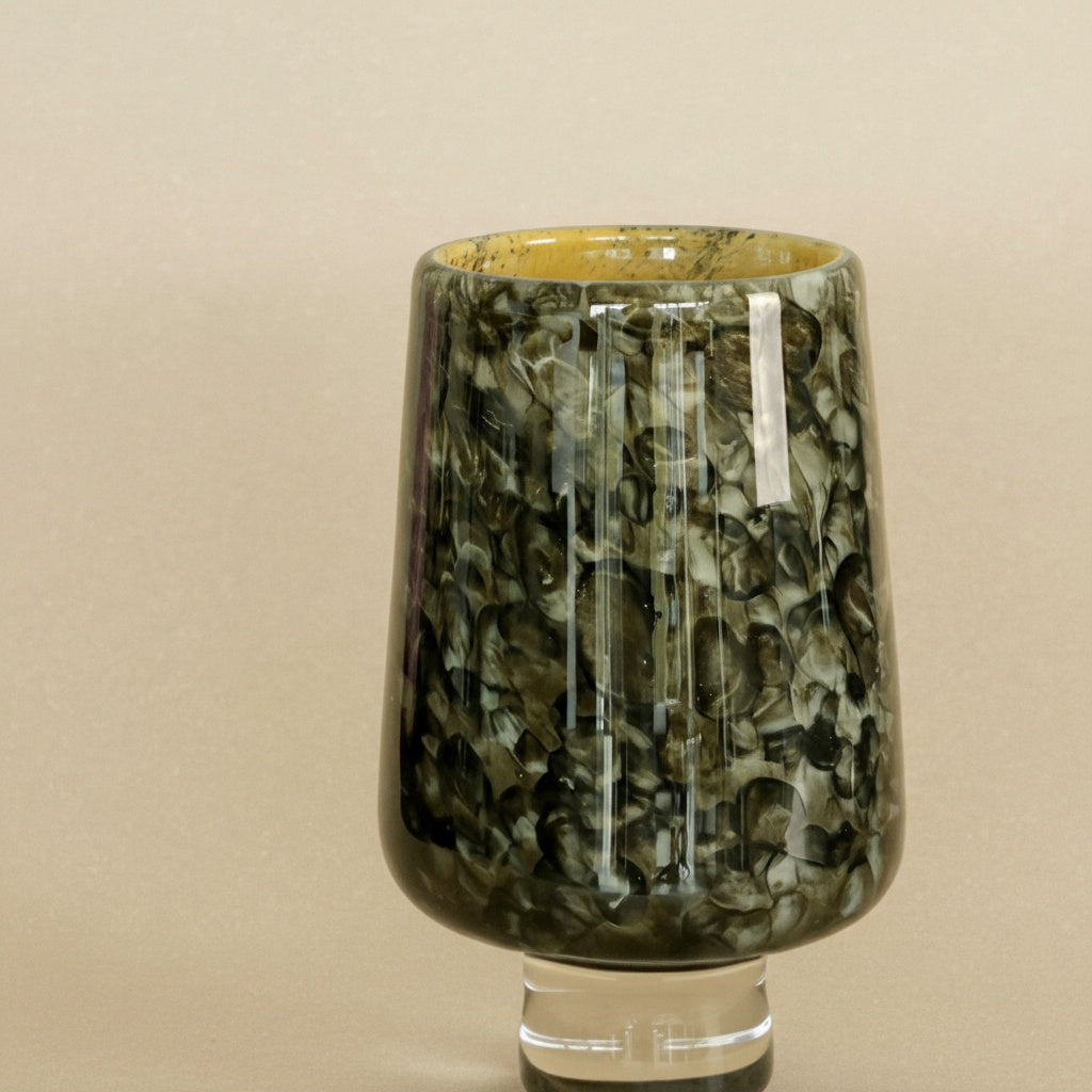 Close up of tall art glass vase with mottled green texture