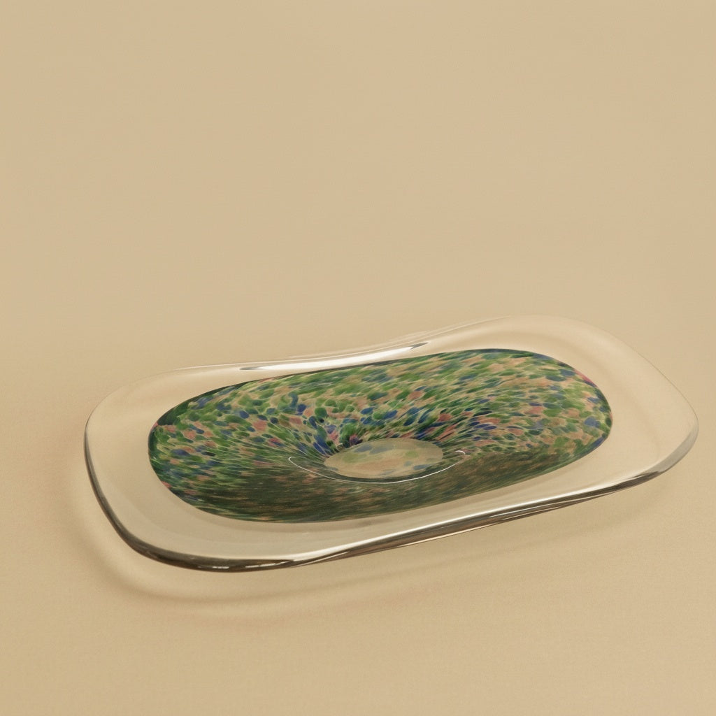 Angled view of oval glass tray with speckled green and blue pattern