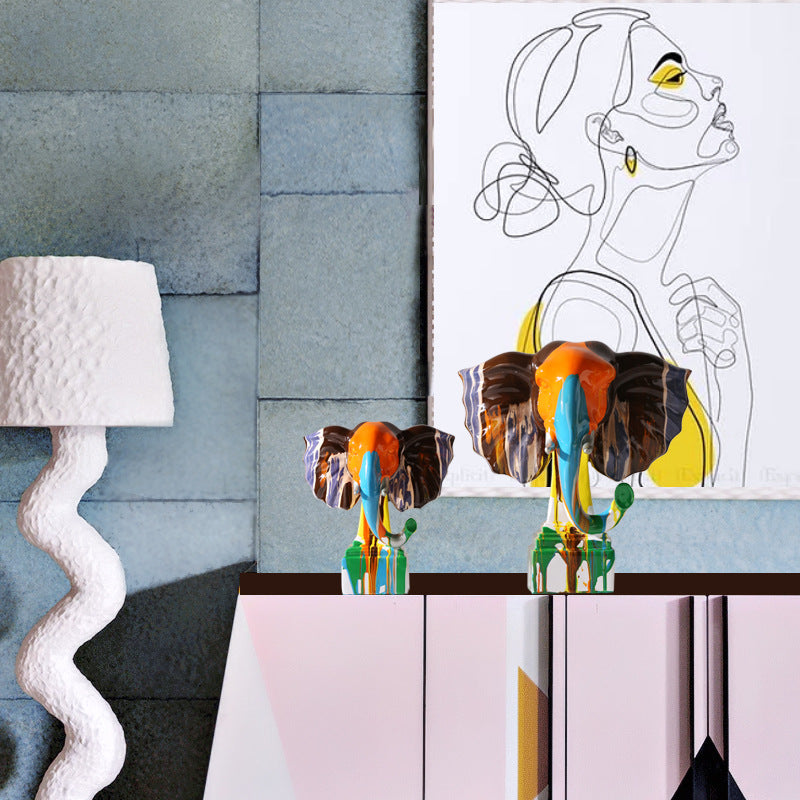 Lifestyle shot of elephant sculptures on a sideboard with art