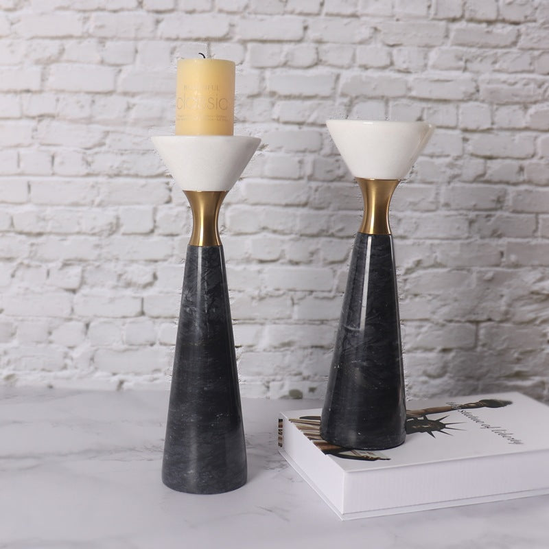 Set of two black marble and brass geometric candle holders on a white brick background