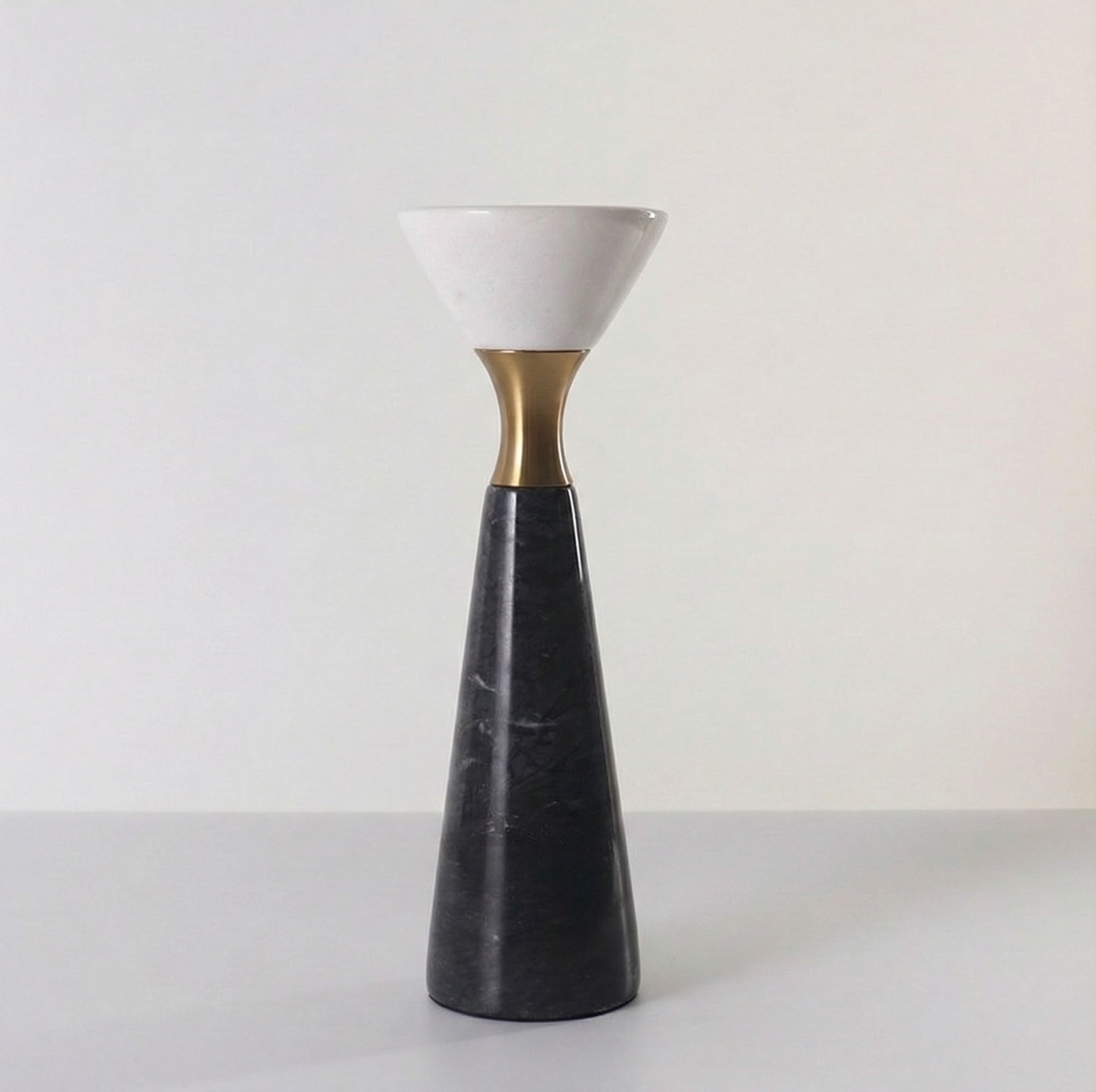 Angled view of sculptural black marble and brass candlestick
