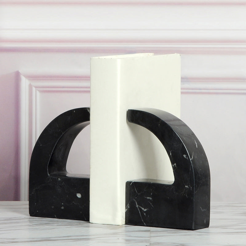 Black marble bookends supporting a book on a marble table showing sturdy construction