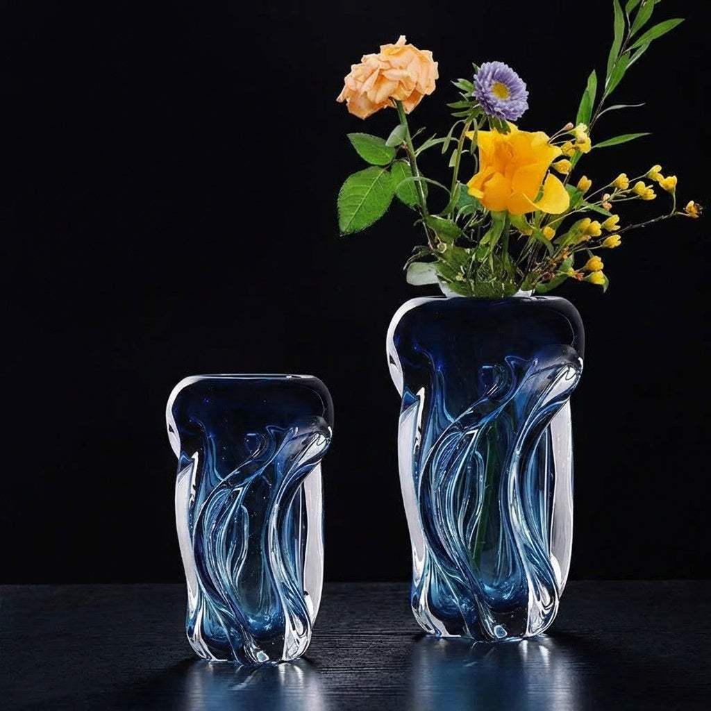 Two blue art glass vases with flowers on a glass table
