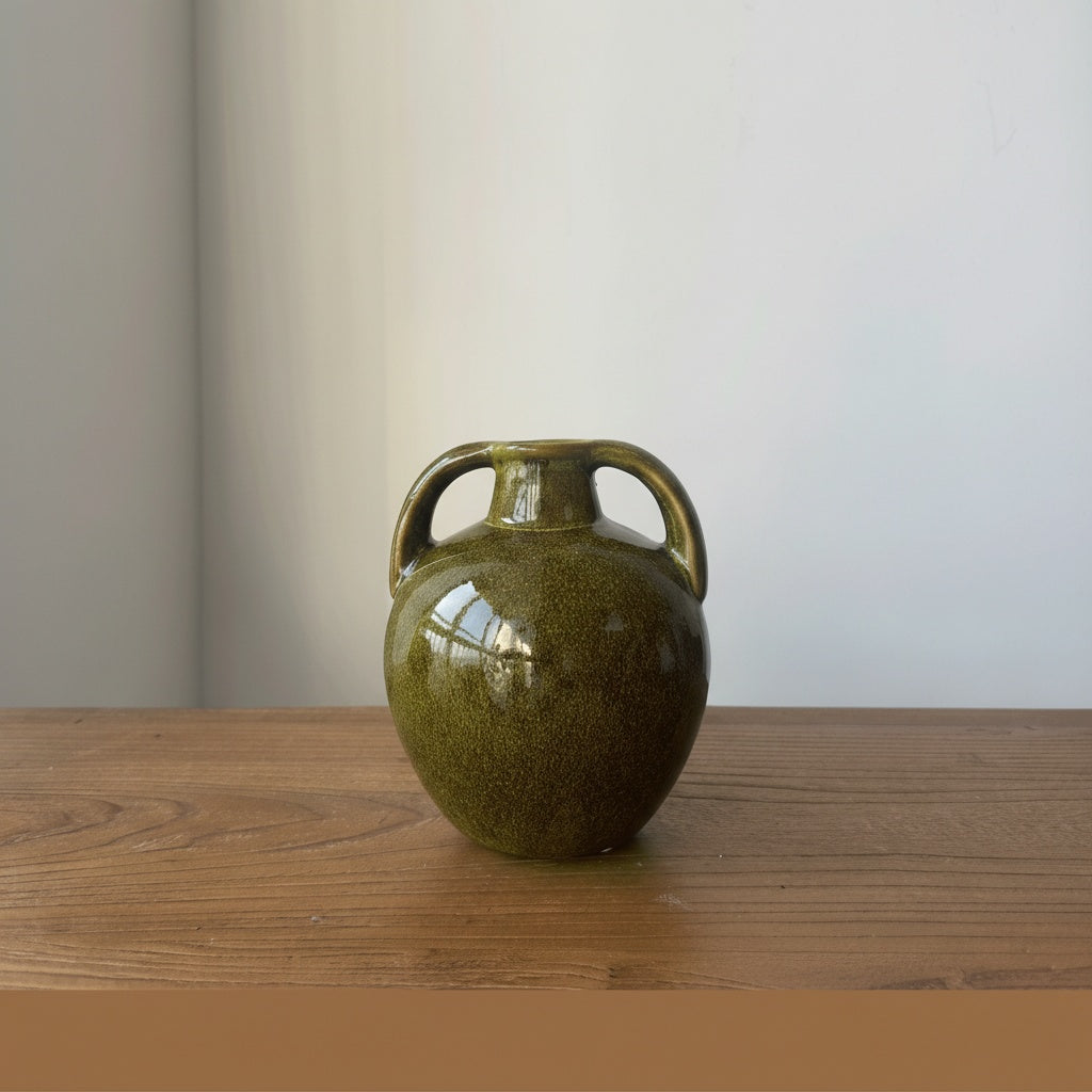 Front view of olive green glazed ceramic amphora vase on wooden table