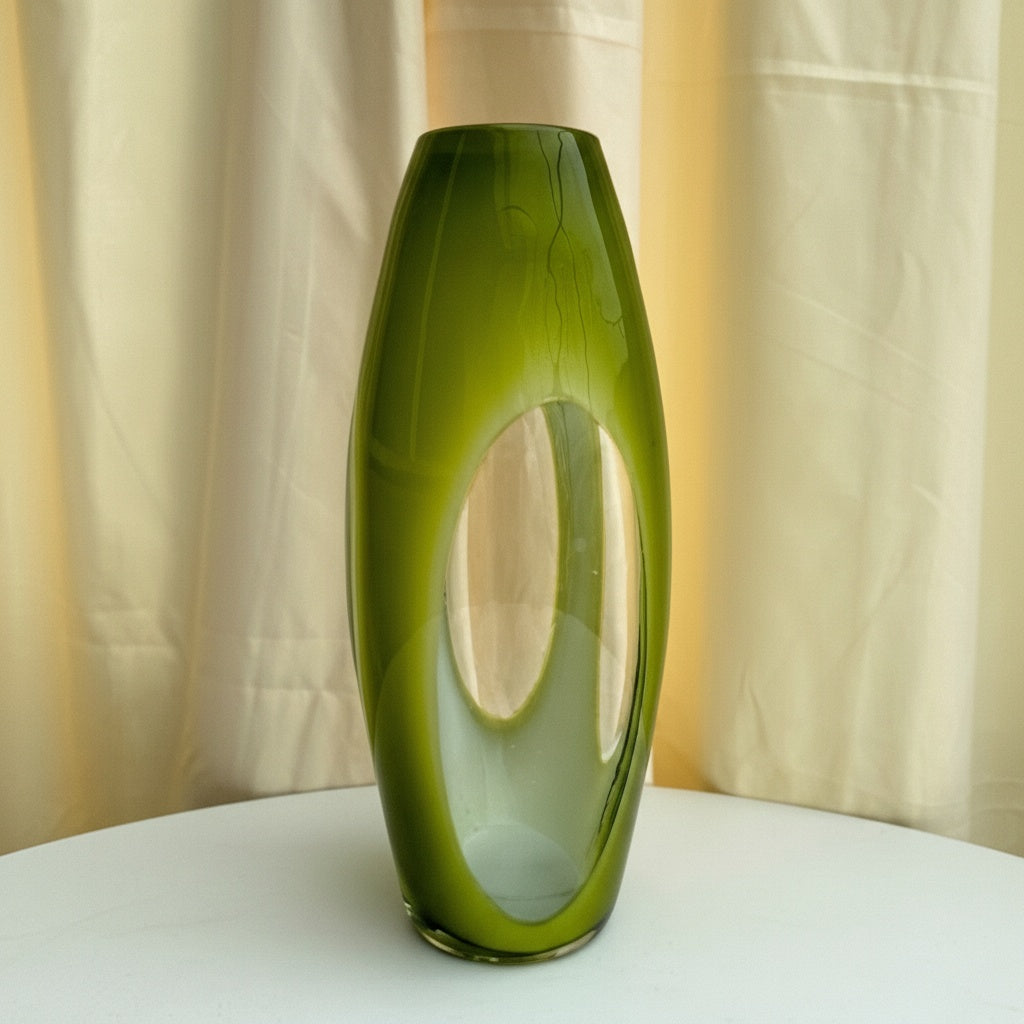 Front view of olive green glass sculptural vase with cutout