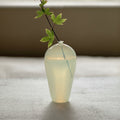 Opaline glass bud vase displaying a single green stem