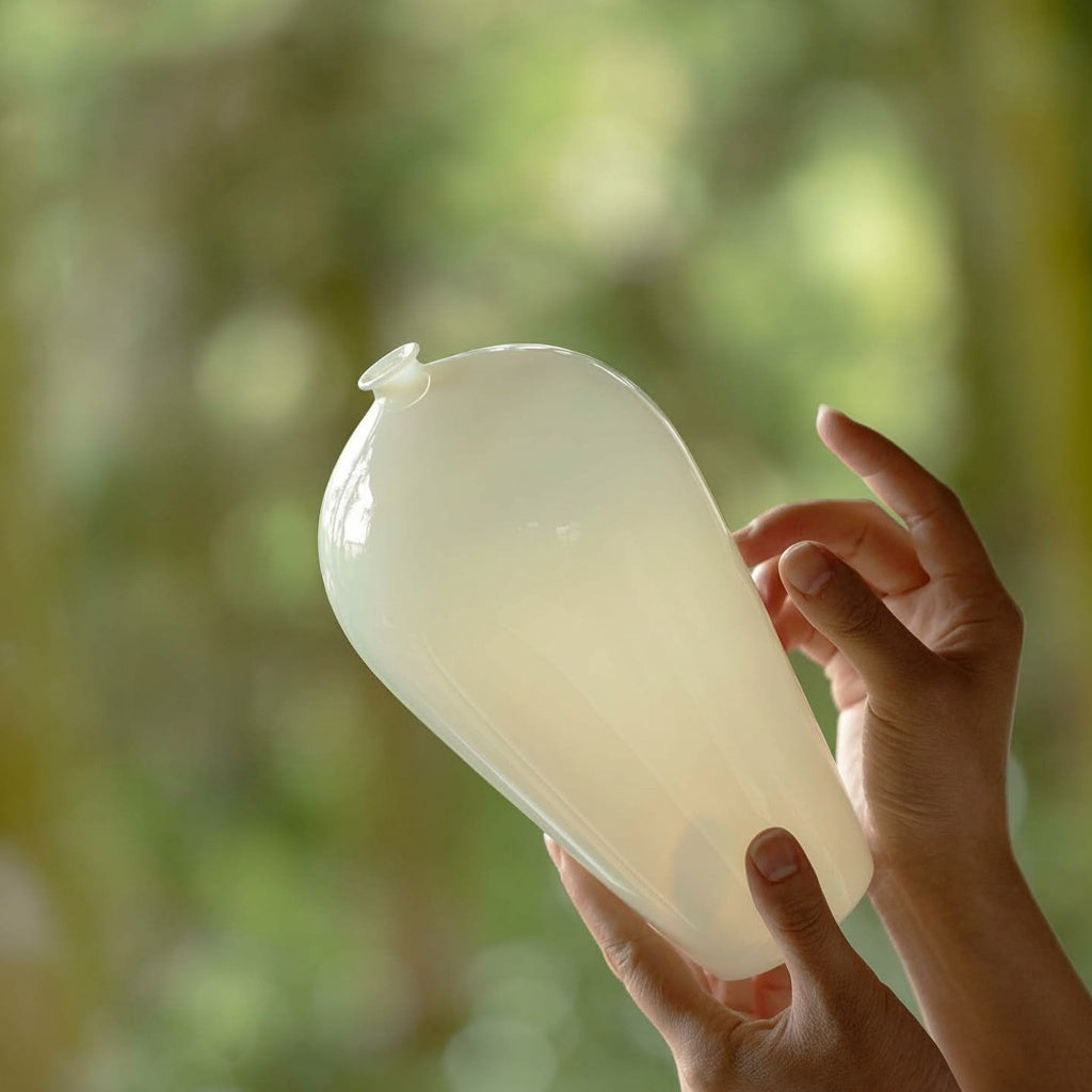 Hands holding translucent milky glass teardrop vase