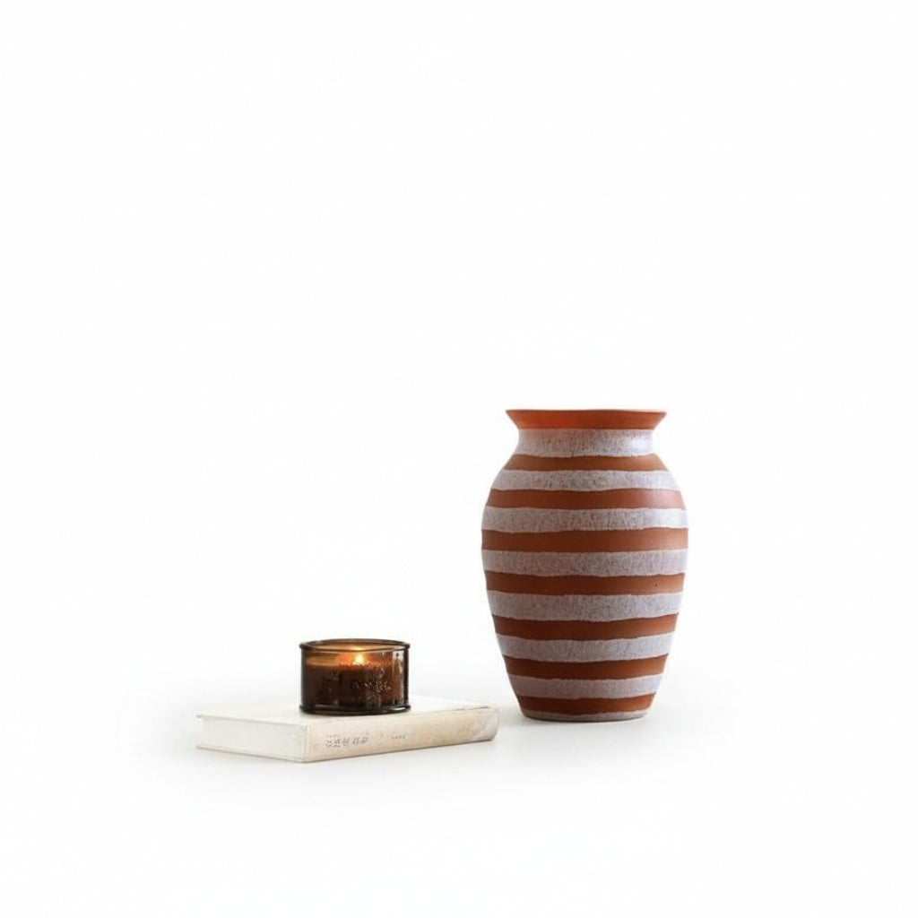 Orange and white striped glass vase styled next to a candle