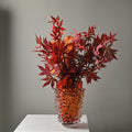 Textured art glass vase in orange with floral arrangement