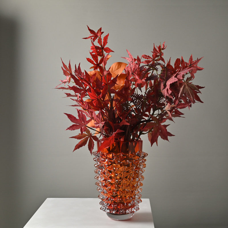 Textured art glass vase in orange with floral arrangement