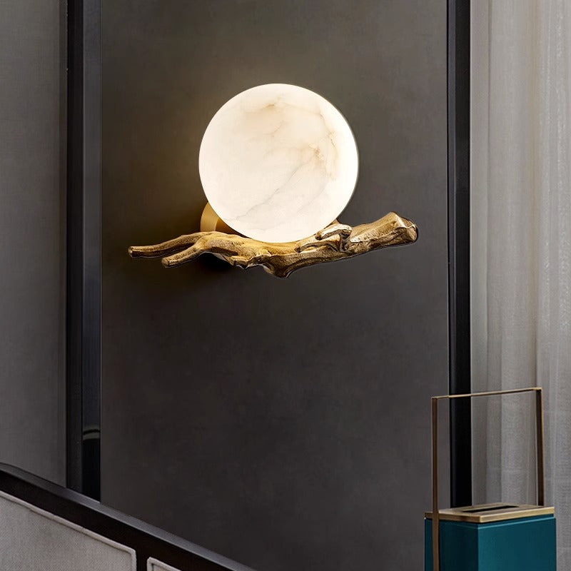 Side profile of sculptural branch wall lamp showing mounting plate and spherical shade