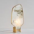Front view of organic white marble and brass table lamp illuminated